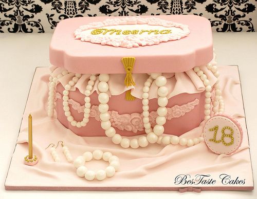 a pink cake with pearls and beads on it