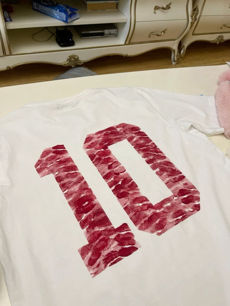 a white t - shirt with the number ten drawn on it and a pink teddy bear