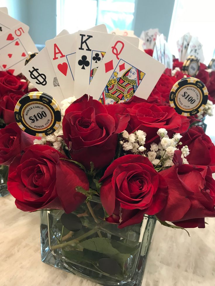 red roses in a vase with playing cards on the table next to eachother