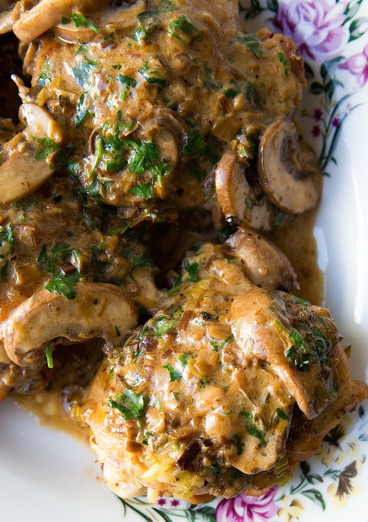 a white plate topped with meat covered in mushroom gravy and garnished with parsley