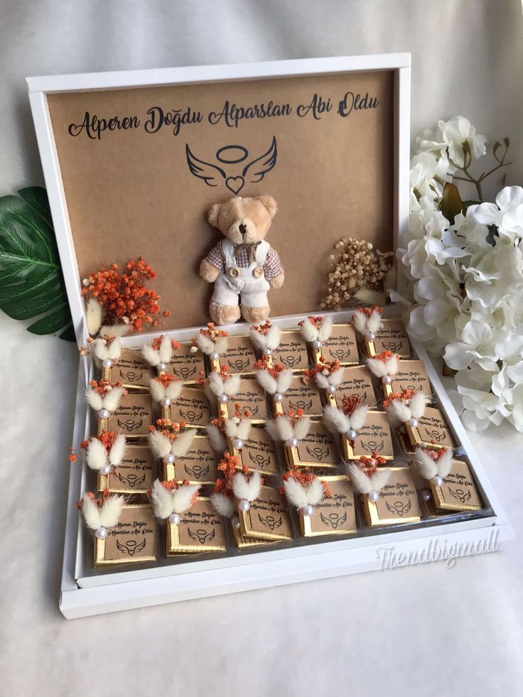 a teddy bear sitting on top of a table next to some chocolates and flowers