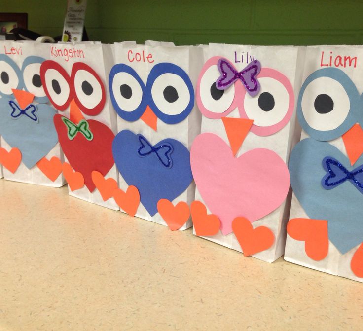 four bags decorated with owls and hearts on a counter top in a classroom or playroom