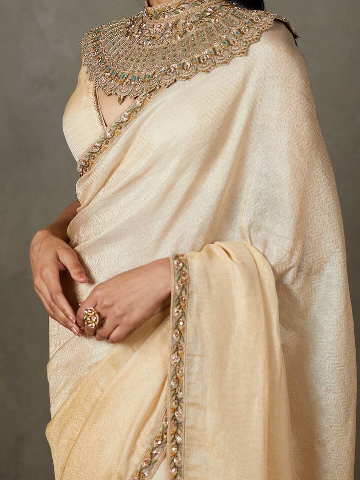 Editor's Note Elevate your traditional style with our off-white/multi machine and hand-embroidered deepali sari, complete with a stitched blouse. This ensemble is perfect for special occasions, allowing you to showcase timeless elegance with intricate embroidery and the convenience of a pre-stitched blouse. Make a lasting impression at any event with this classic and sophisticated attire that combines tradition with modern comfort. Fabric: Nilambari silk with zari Color: Off-white Components: Sa Luxury Gold Embroidered Art Silk Traditional Wear, Festive Pre-draped Saree With Embroidered Border In Cotton Silk, Festive Cotton Silk Pre-draped Saree With Embroidered Border, White Cotton Silk Pre-draped Saree With Zari Work, Traditional Cotton Silk Pre-draped Saree With Embroidered Border, Traditional Off White Chanderi Pre-draped Saree, Traditional Pre-draped Cream Saree, Transitional Pre-draped Cotton Silk Saree With Embroidered Border, White Blouse For Eid Reception