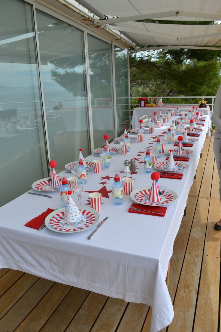 a long table is set up with red and white striped paper cups, plates and napkins