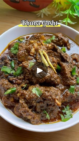 a white bowl filled with meat and garnished with cilantro on top