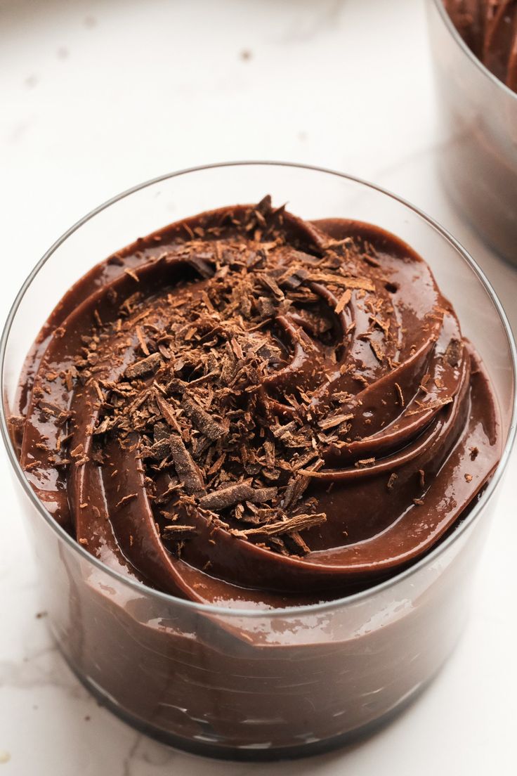 a chocolate dessert in a glass bowl on a table with two bowls full of it