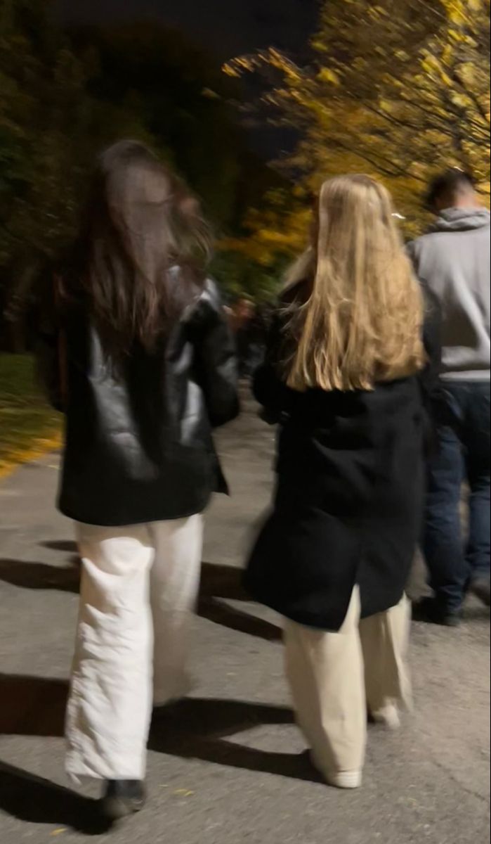 two women walking down the street with their hands in each other's back pockets