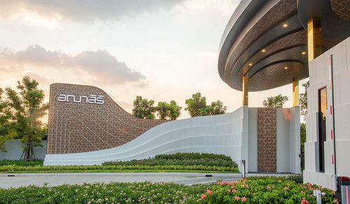 the entrance to an office building with flowers and bushes in front of it at sunset