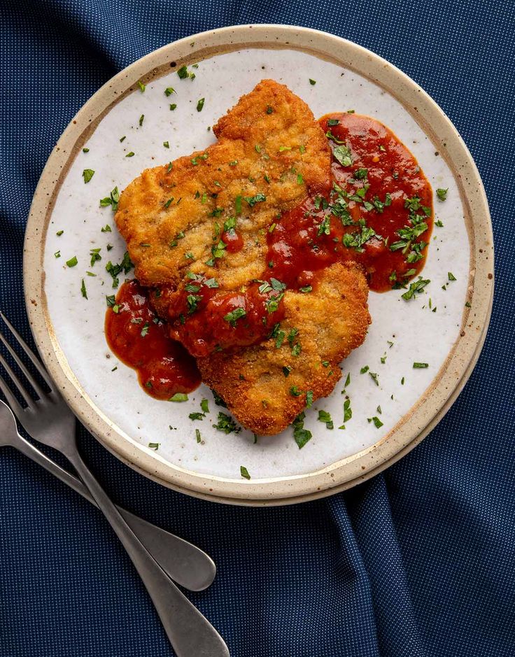 a white plate topped with meat patties covered in marinara sauce