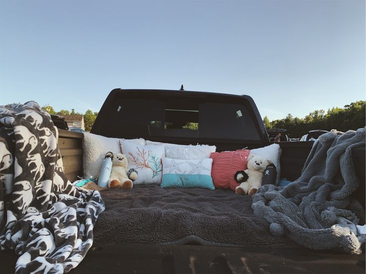 the back end of a truck with pillows and blankets on it's flatbed