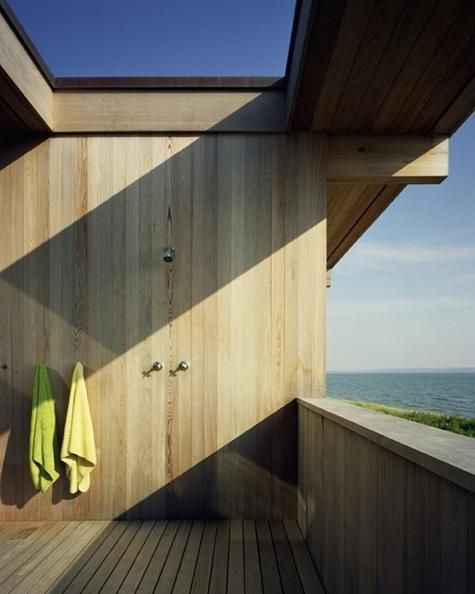 a wooden deck with two towels hanging on it's side and the ocean in the background