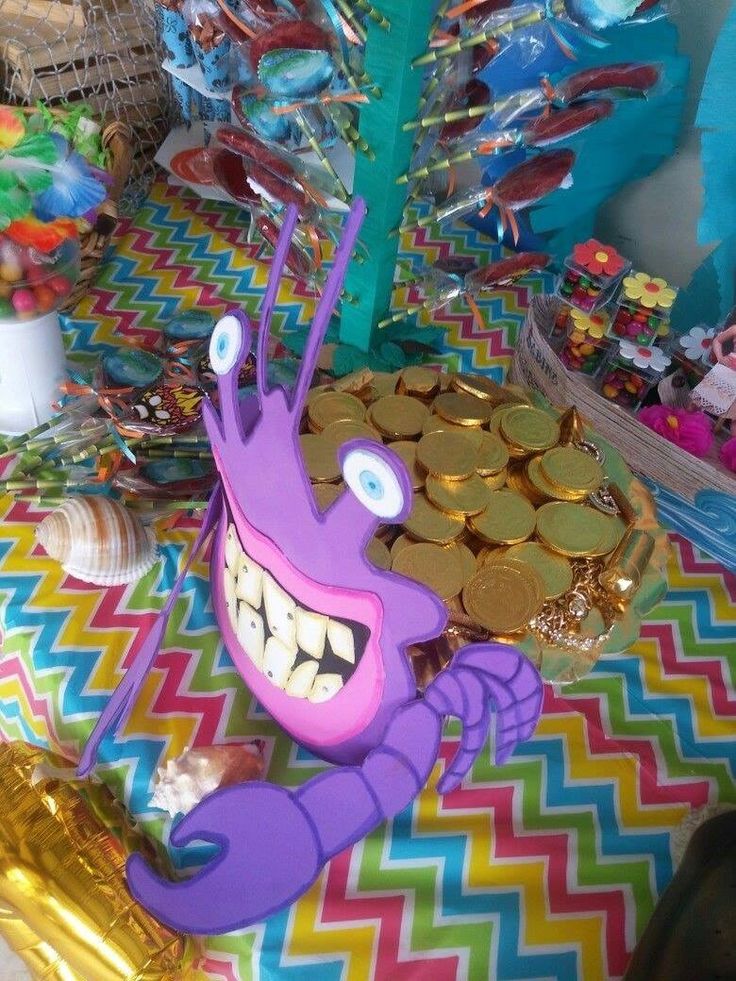 a table topped with lots of candy and candies next to a tree filled with gold coins