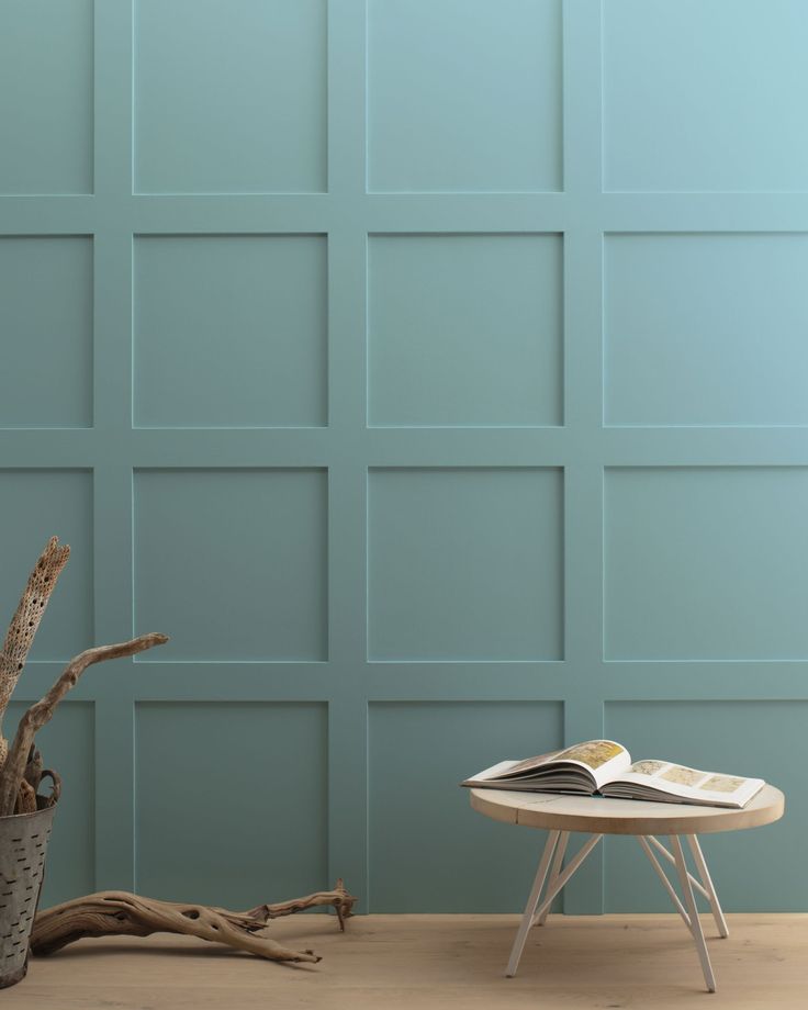 a small table with a book on it in front of a wall painted teal