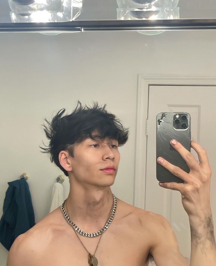 a shirtless man taking a selfie in front of a mirror with his cell phone