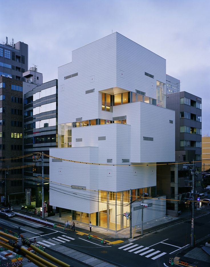 the building is white and has many windows on each side, along with other buildings