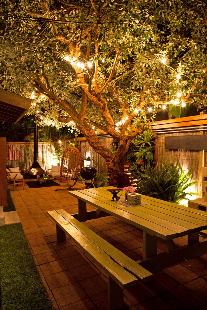 a wooden table under a tree with lights on it