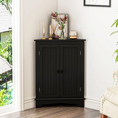 a black cabinet sitting in the corner of a room next to a chair and potted plant