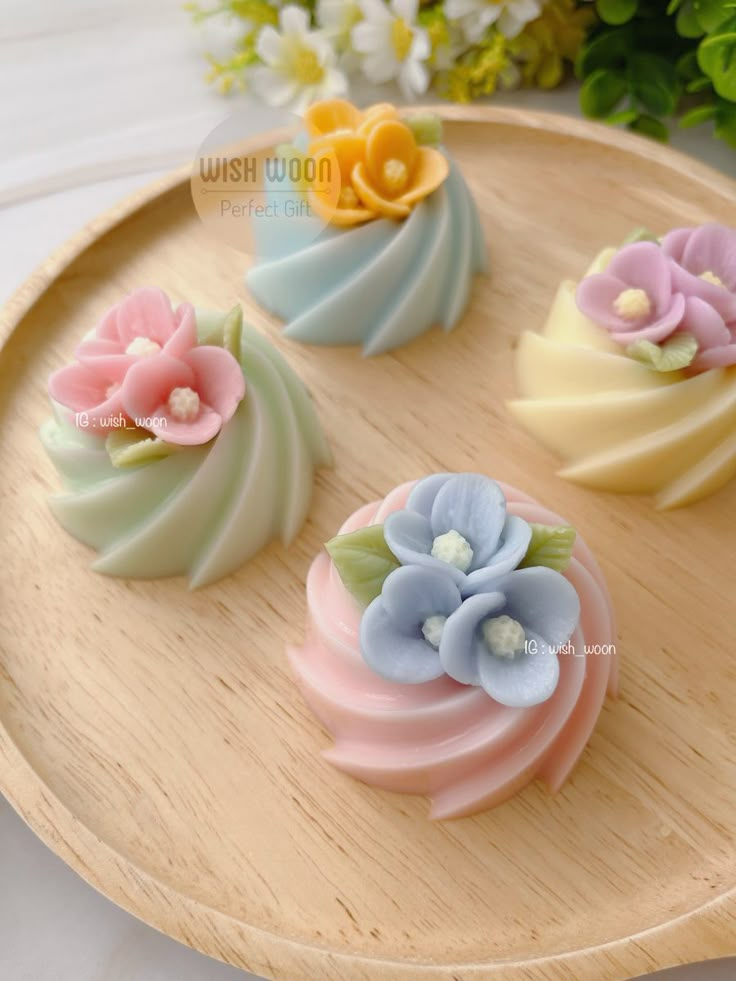 four different colored flowers on a wooden tray