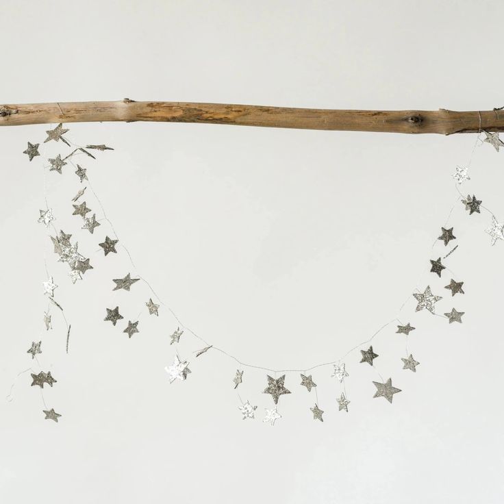 silver stars are hanging from a wooden branch