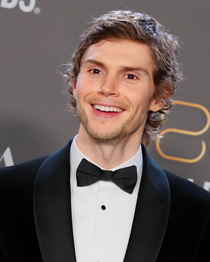 a man in a tuxedo smiles at the camera