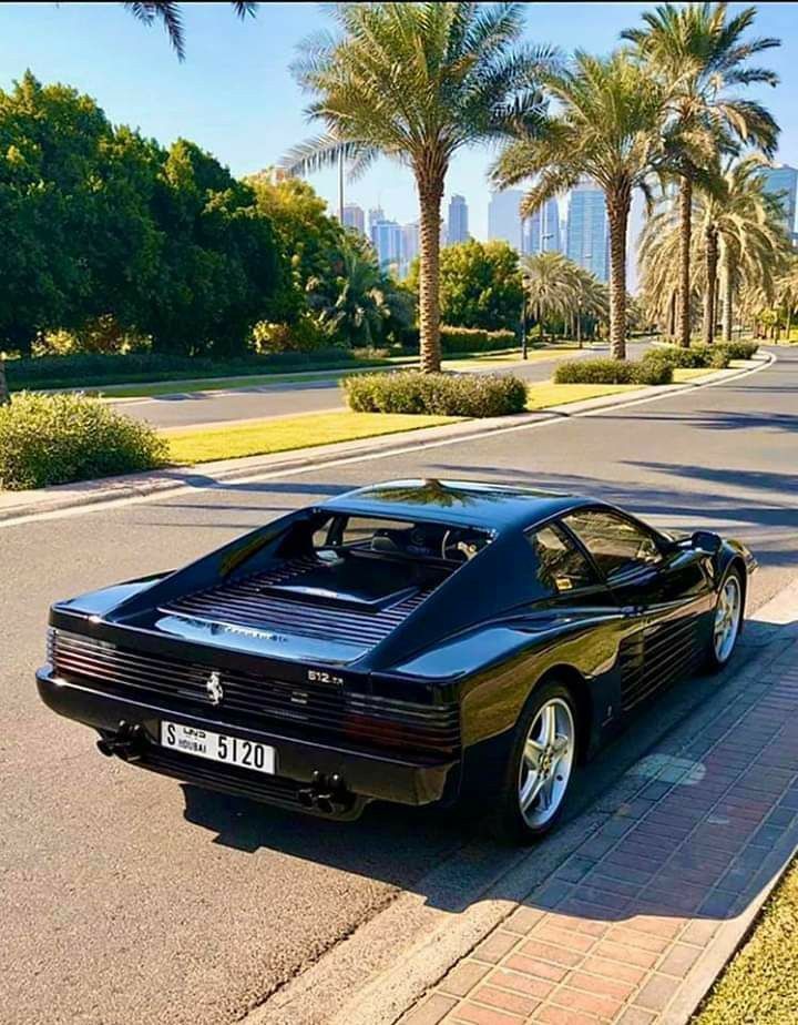 a black sports car is parked on the side of the road in front of palm trees