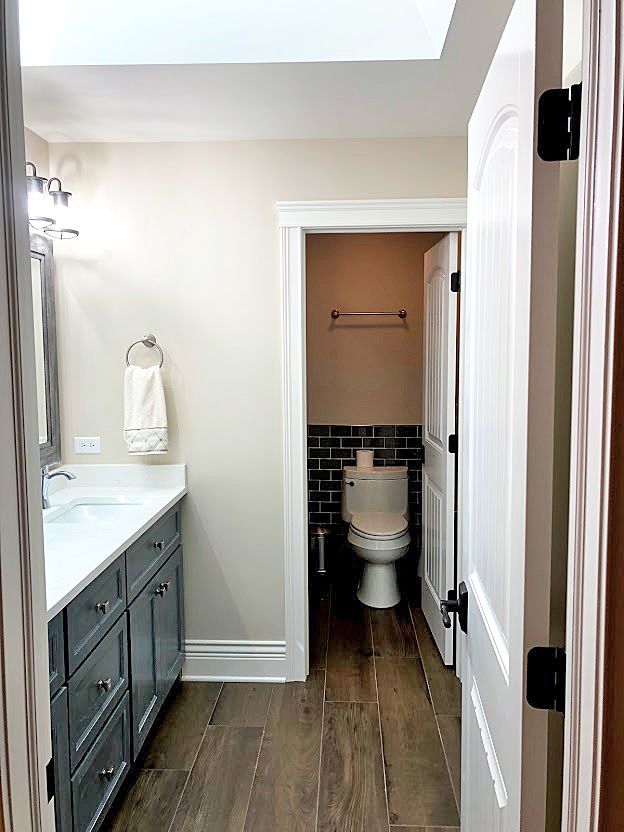 a bathroom with wood floors and white walls