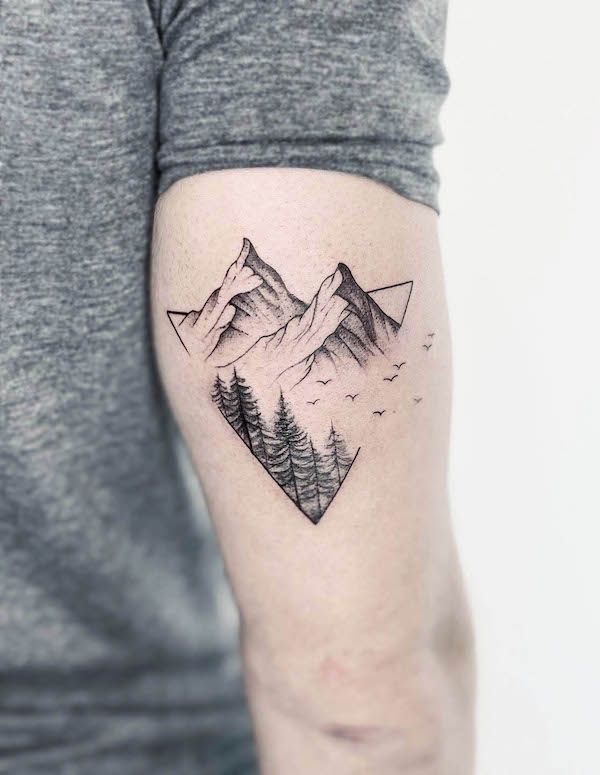 a man's arm with mountains and trees tattoo on the back of his arm