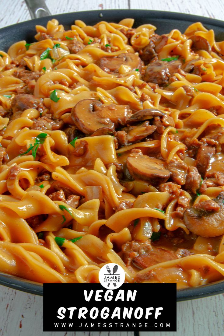 a pan filled with pasta and meat on top of a wooden table