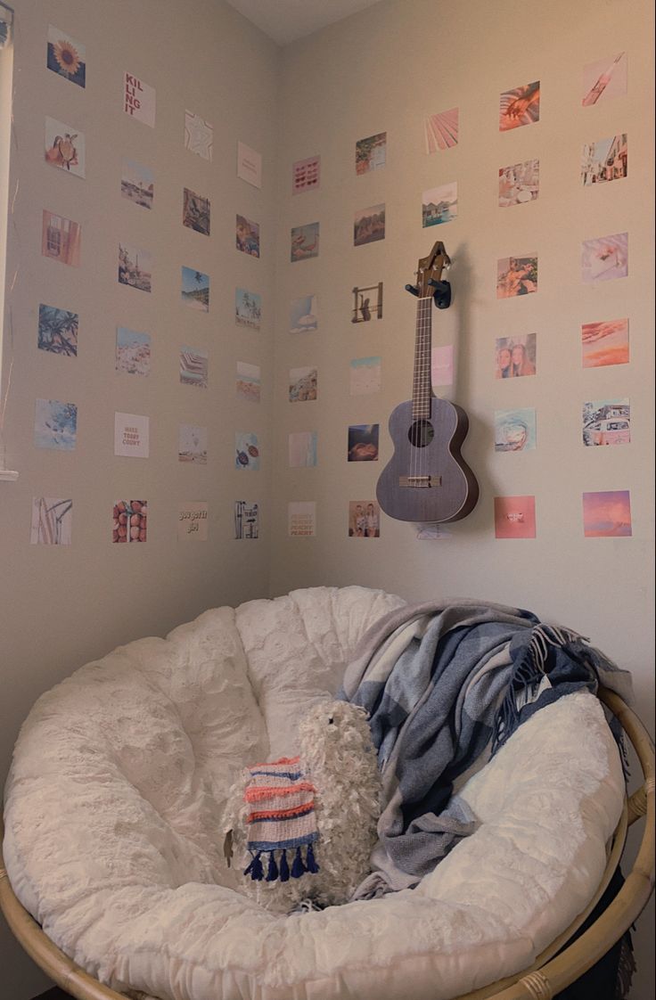 a white dog bed with a stuffed animal in it's lap next to a guitar on the wall