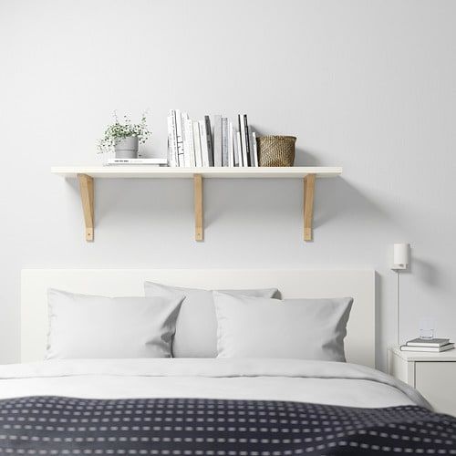 there is a bed with white sheets and pillows on the headboard, along with two bookshelves above it