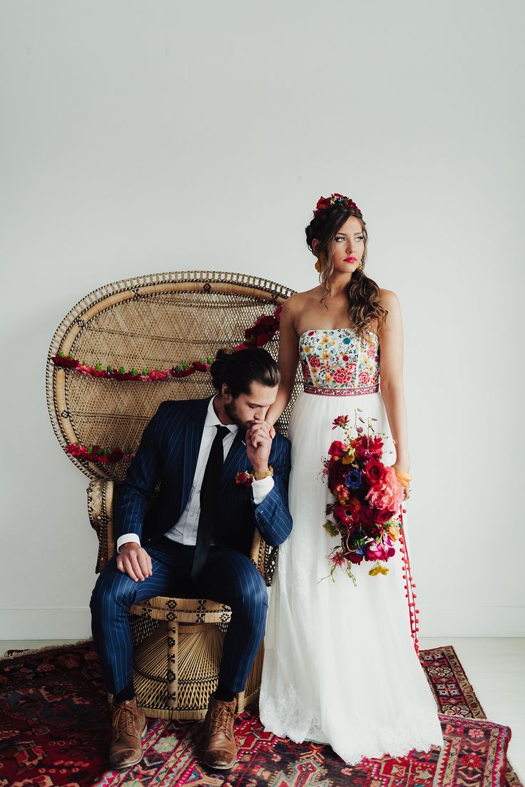 a bride and groom sitting on a wicker chair in front of a white wall