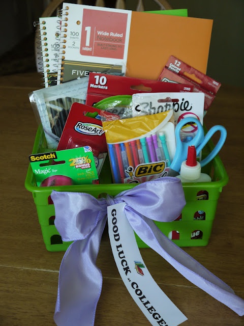 a green basket filled with school supplies on top of a wooden table next to a white ribbon