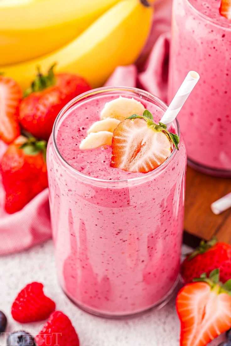 two glasses filled with smoothie next to bananas and strawberries