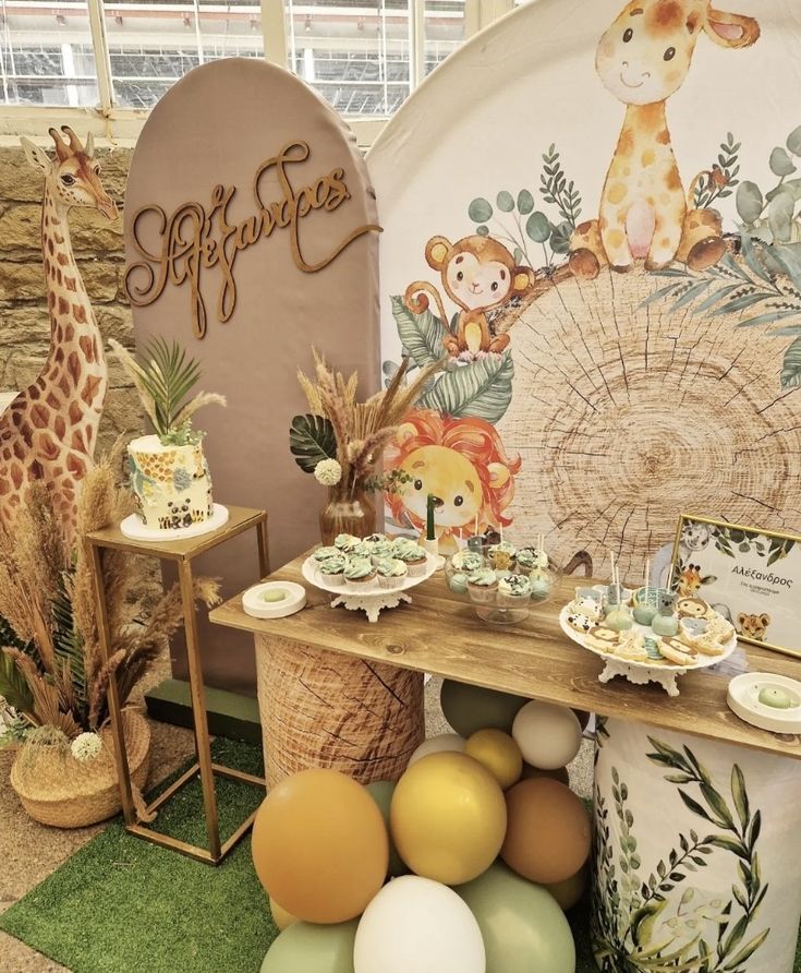 an animal themed birthday party with balloons and desserts on the buffet table in front of a giraffe backdrop