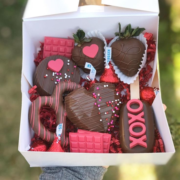 a box filled with chocolate covered strawberries and heart - shaped candies in the shape of hearts