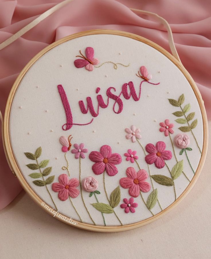 a hand embroidered name with pink flowers and butterflies