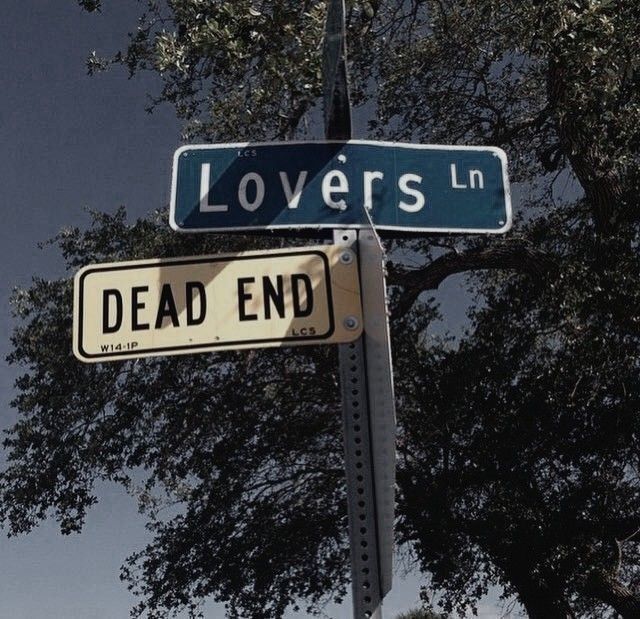 a street sign that says lovers lane and dead end on it's pole with trees in the background