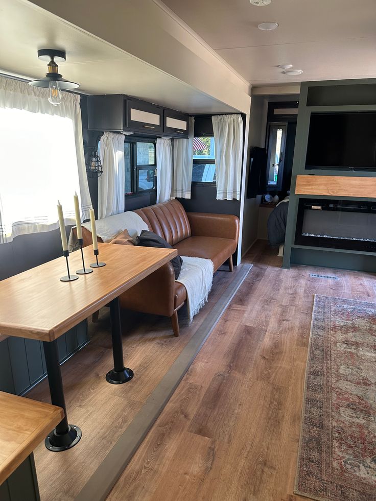 a living area with couches, table and television in an airstream style home