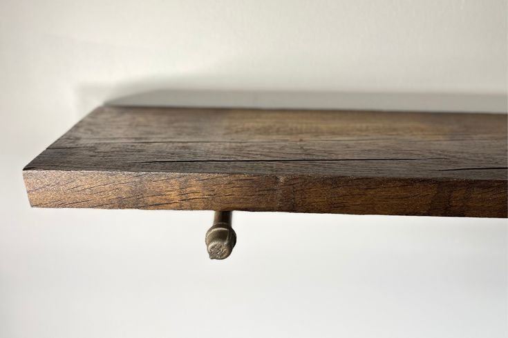 a close up of a wooden shelf with two nails on the top and one nail in the middle