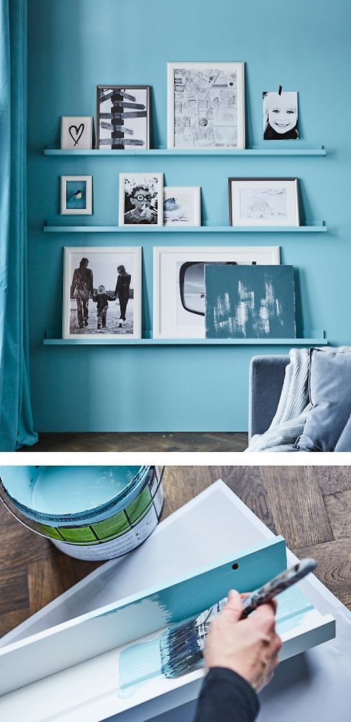 a person holding a piece of paper in front of some pictures on the wall and shelves