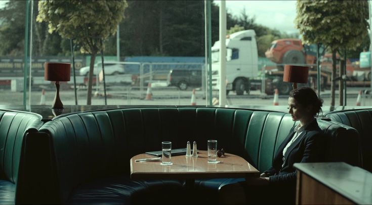 two men sitting at a table in a restaurant, one is talking to the other