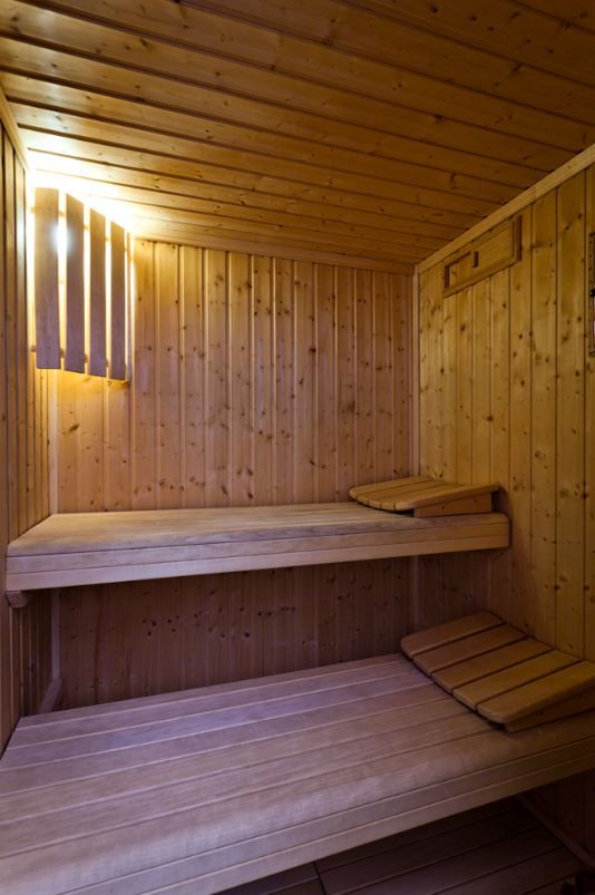 a wooden sauna with two benches and lights on the wall above it, in a wood - paneled room