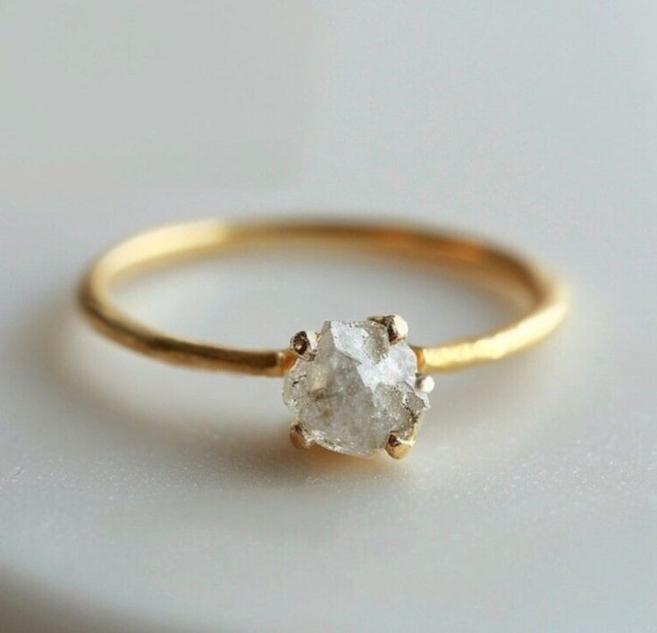 a gold ring with a white diamond on it's side, sitting on a table