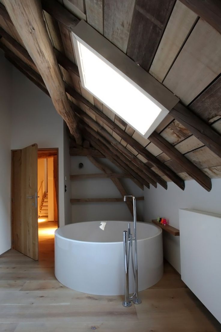 an instagram photo of a bathroom with a skylight above the bathtub and stairs