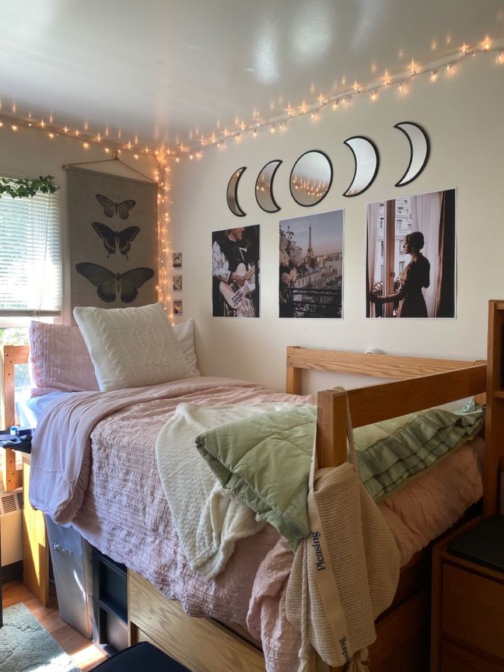 a bedroom with lights strung from the ceiling and pictures on the wall above the bed