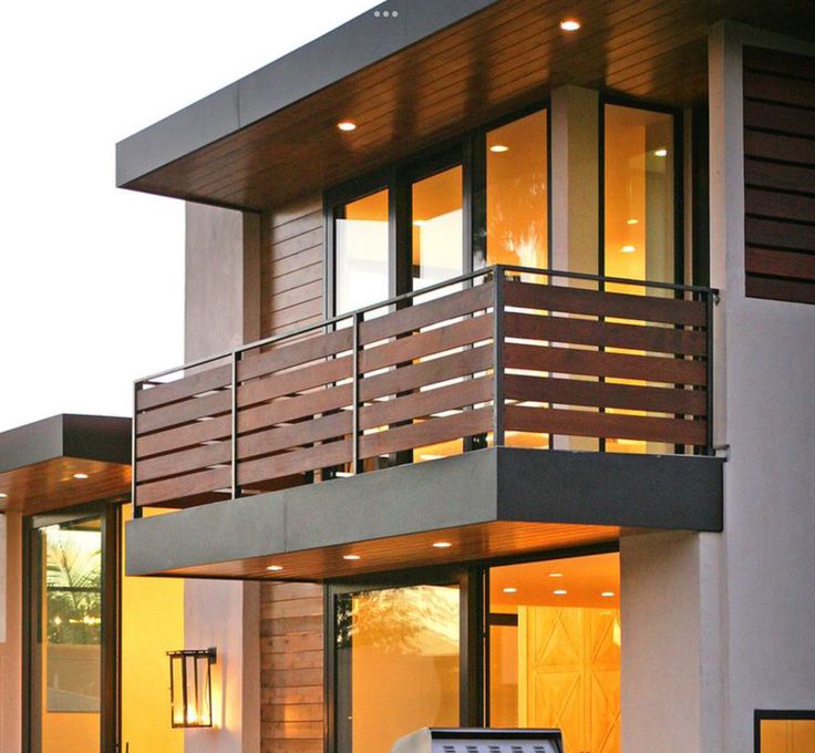 a modern house with wood and glass balconies on the balcony, lights above it