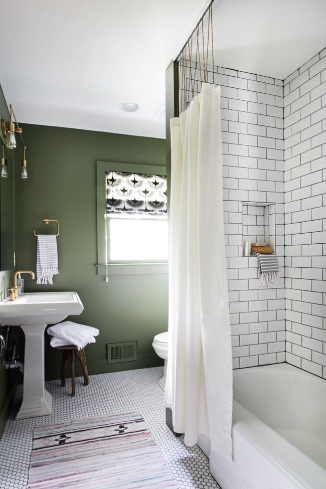 a bathroom with green walls and white tile on the floor, along with a shower curtain