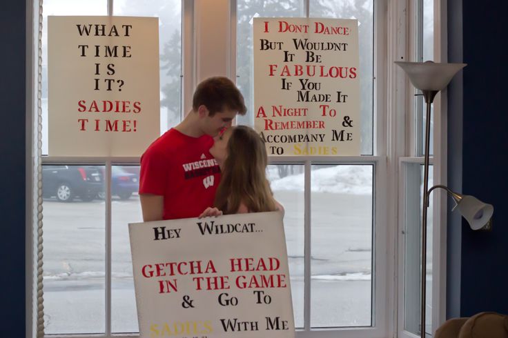 a man and woman standing in front of a window with signs on the windowsill