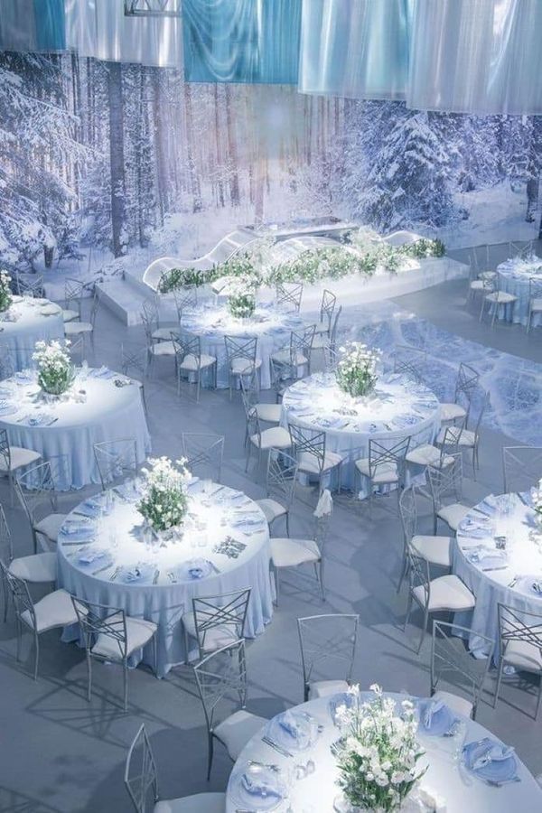 tables and chairs are set up in the middle of a snowy area with white tablecloths