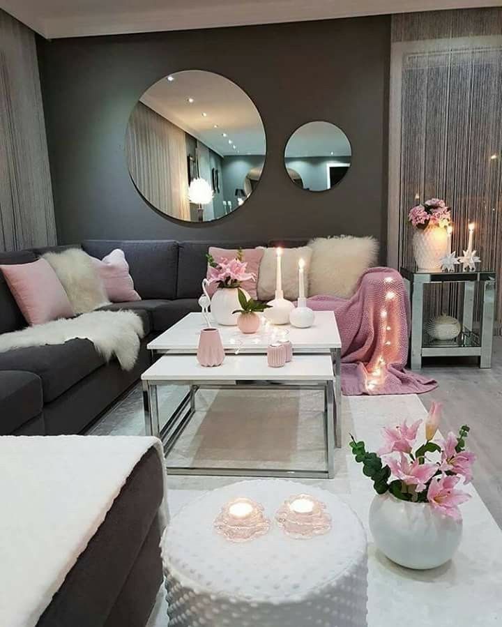 the living room is decorated in pink and grey tones with candles on the coffee table